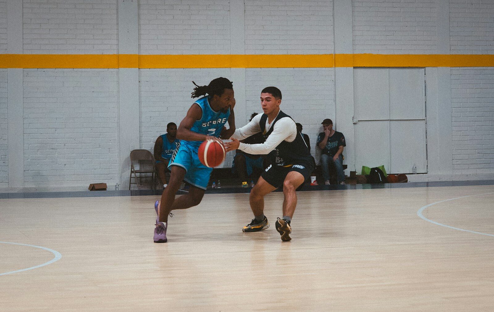 Two basketball players dribbling and defending on court.